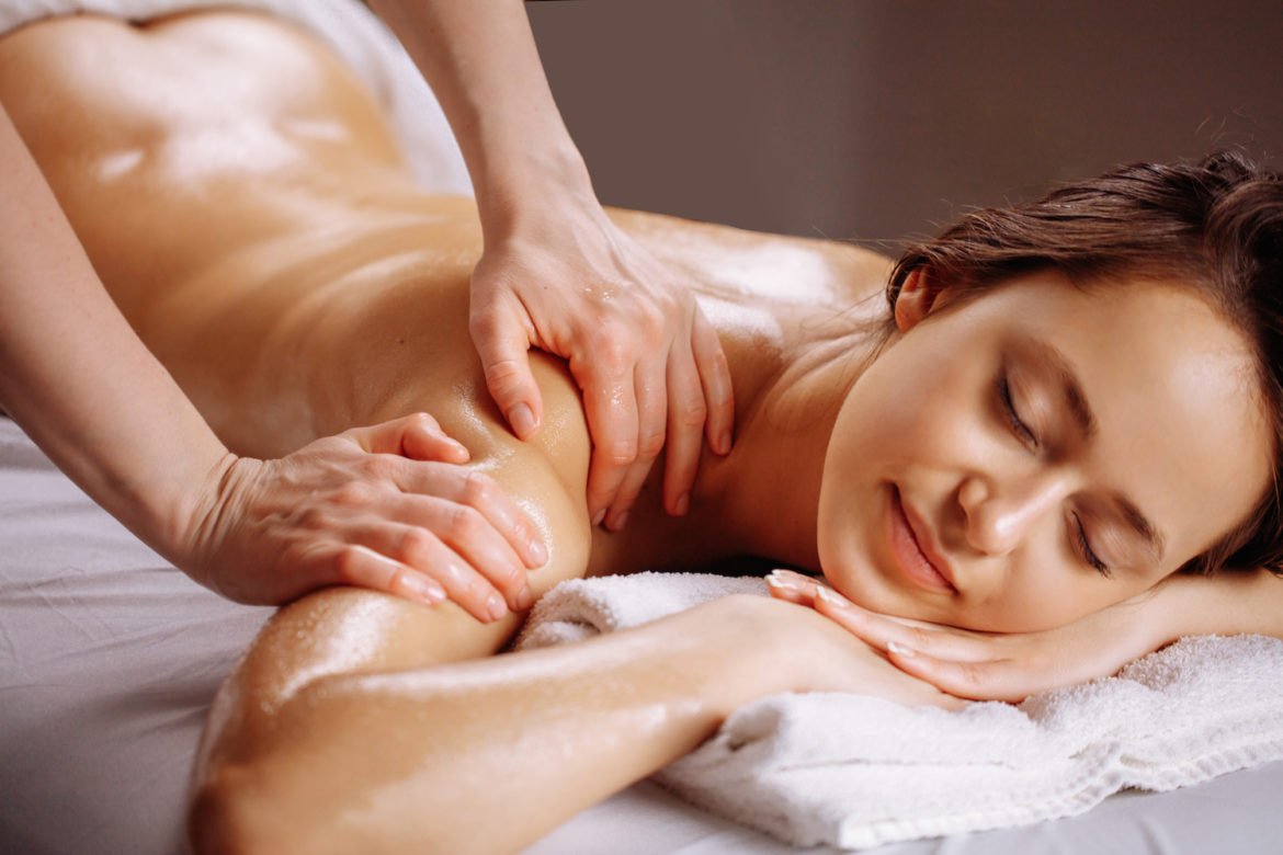 relaxing woman getting spa massage of shoulder in beauty salon